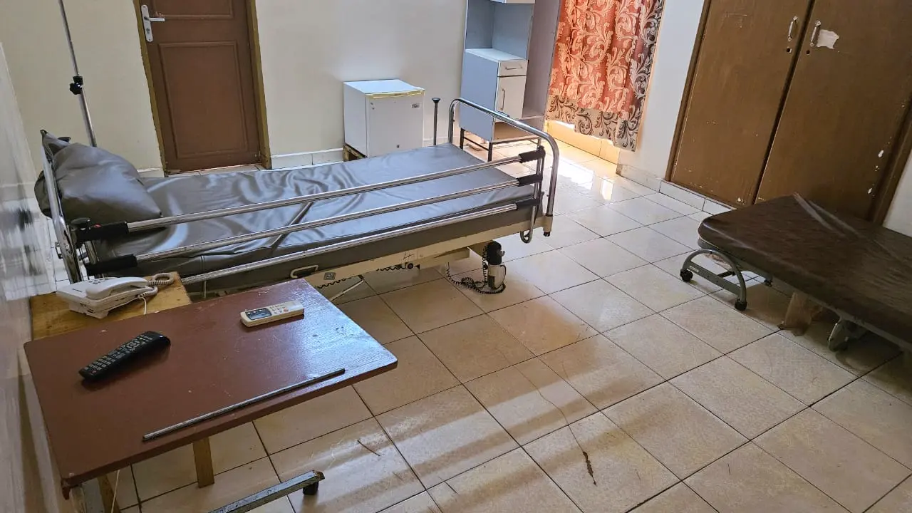 Chambre du Centre médical de l’Espérance avec lit médicalisé, réfrigérateur et espace assis